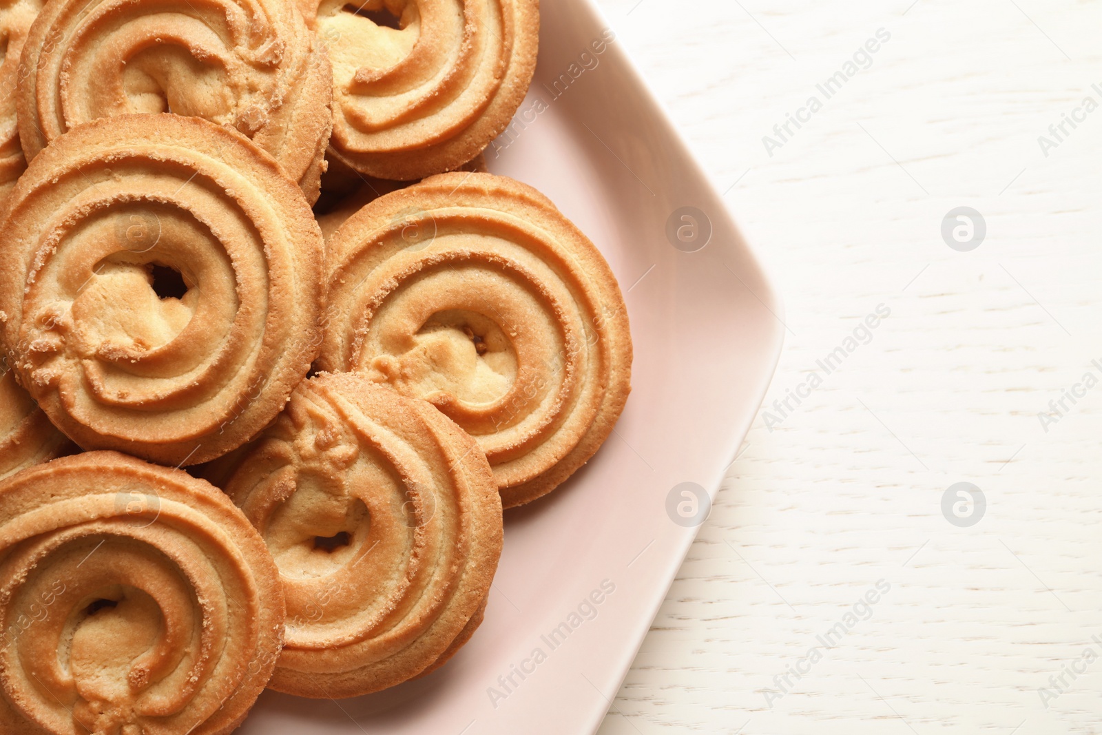 Photo of Plate with Danish butter cookies on wooden table, top view. Space for text