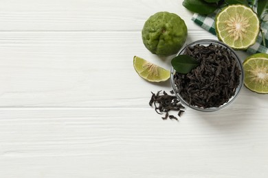 Photo of Dry bergamot tea leaves and fresh fruits on white wooden table, flat lay. Space for text