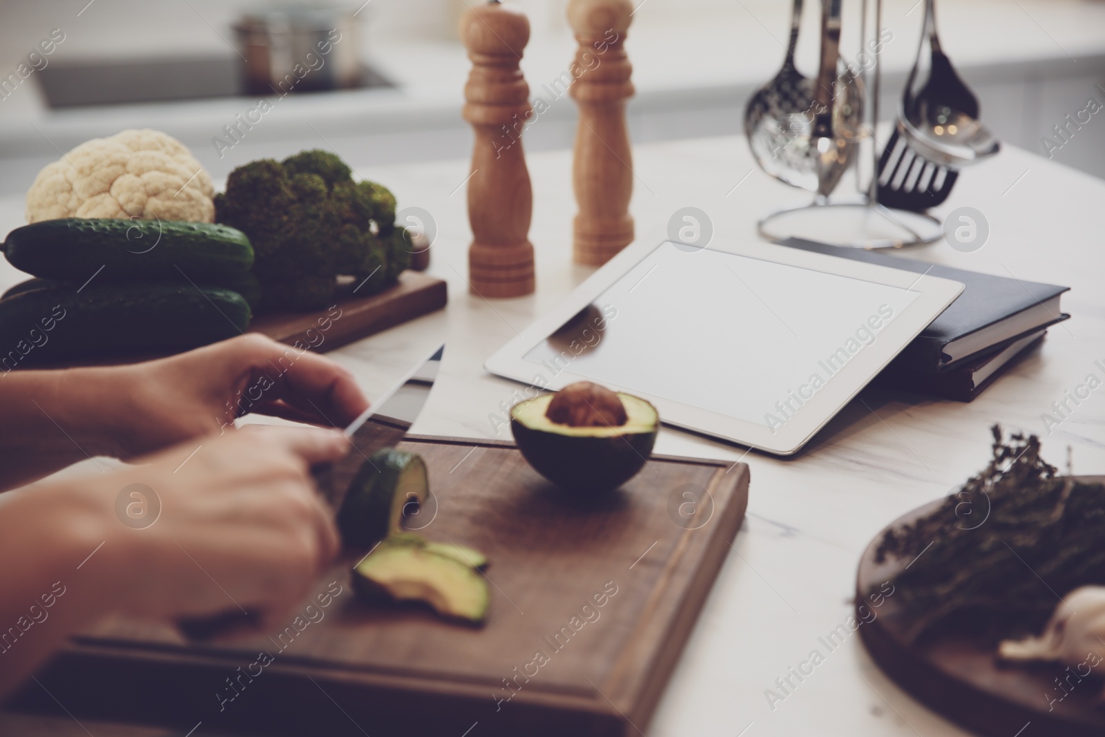 Photo of Woman with tablet cooking at table in kitchen, closeup