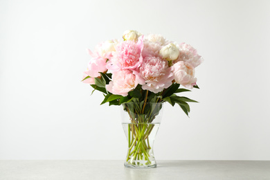 Beautiful peony bouquet in vase on table against white background