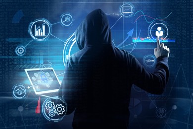 Man in hood with laptop and digital icons on dark background. Cyber attack concept