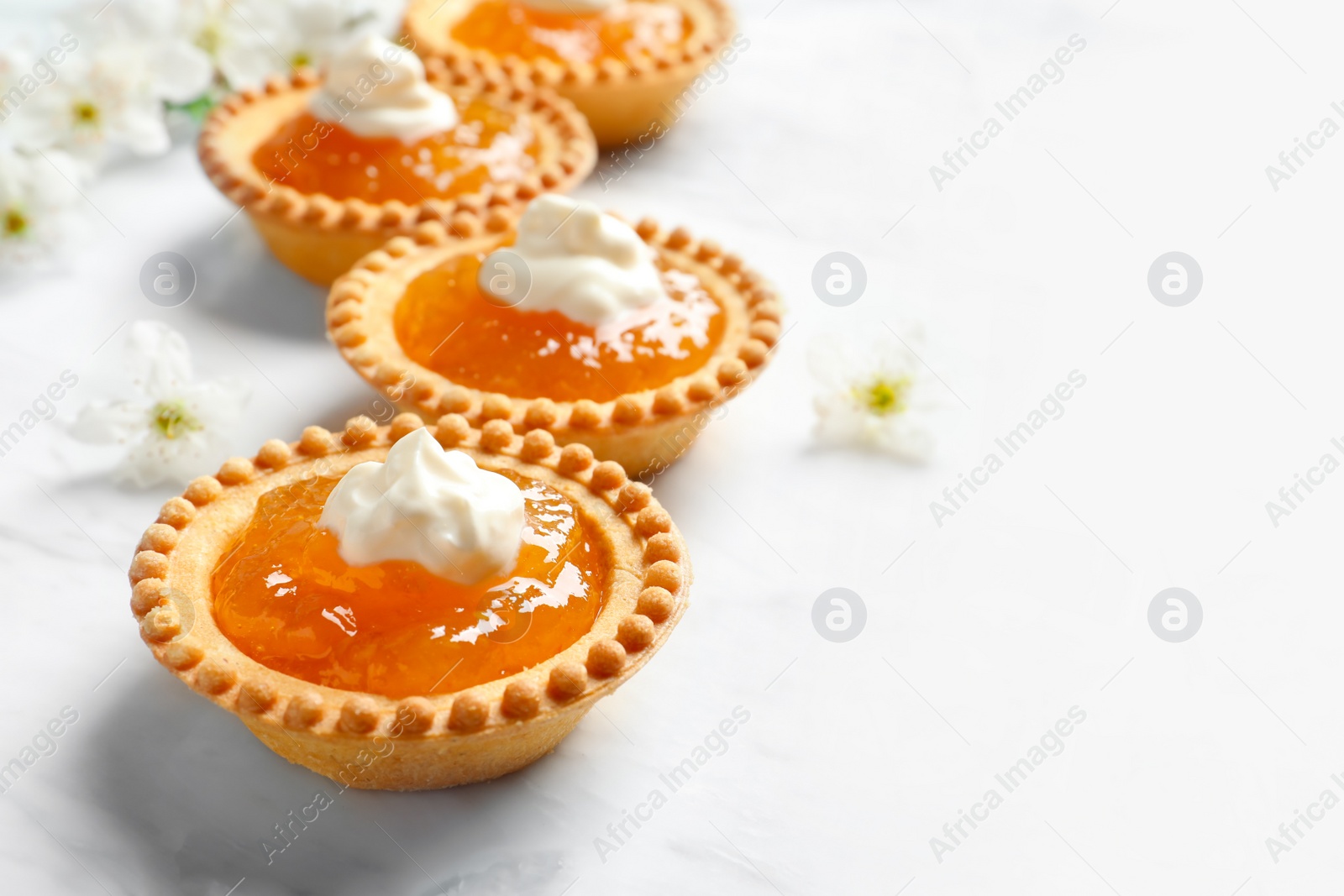 Photo of Tasty tartlets with jam on light background, closeup