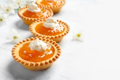 Tasty tartlets with jam on light background, closeup