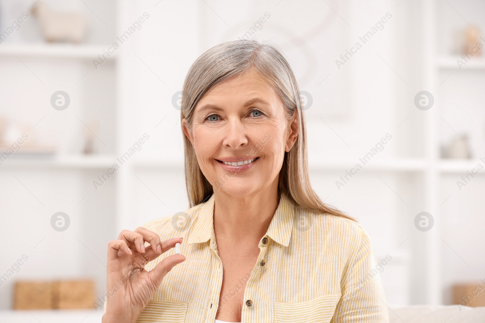 Photo of Menopause, hormone replacement therapy. Happy woman holding pill at home