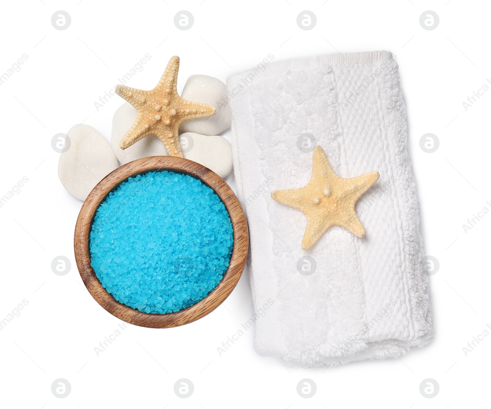 Photo of Light blue sea salt in bowl, spa stones, starfishes and towel isolated on white, top view