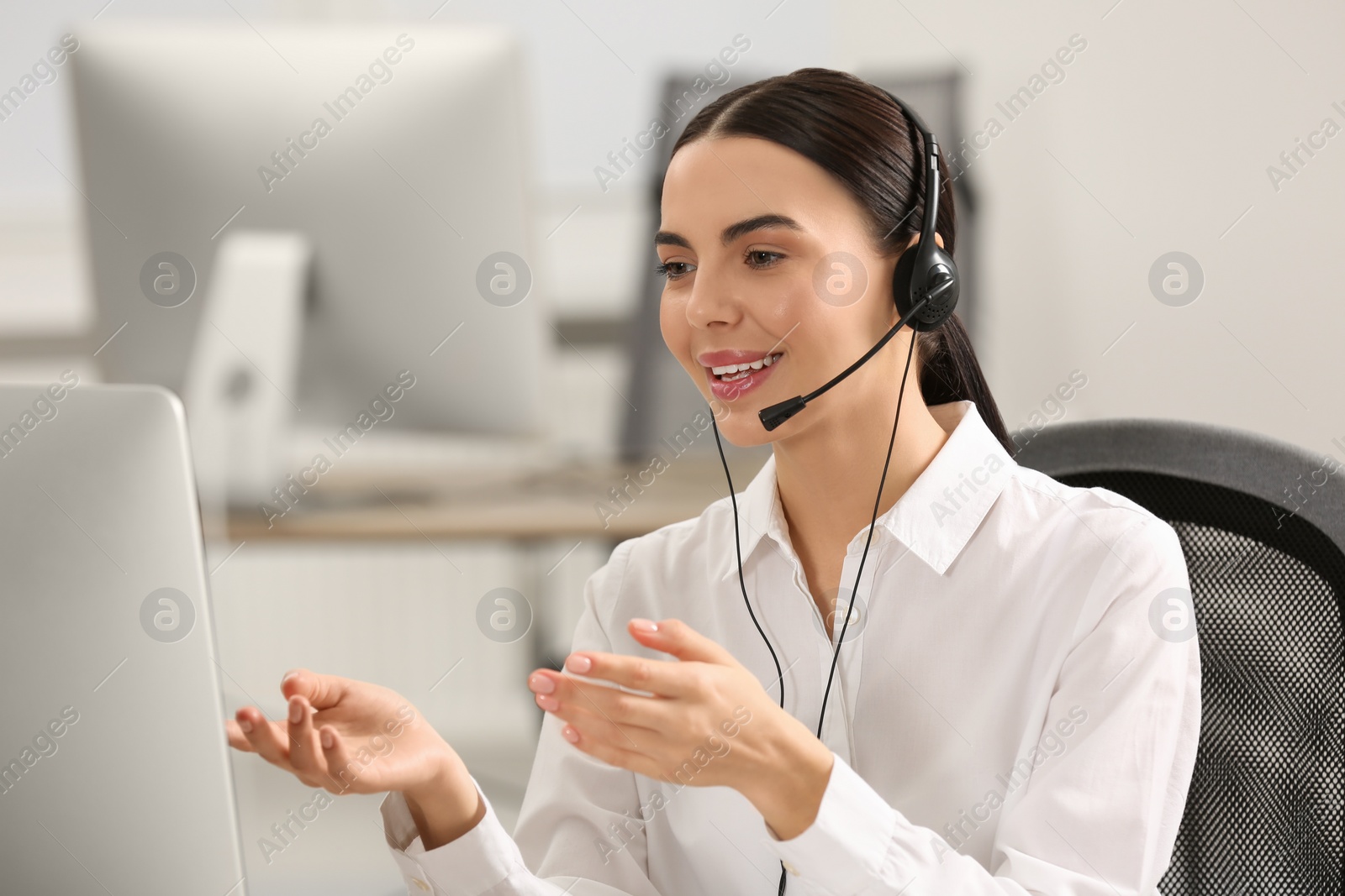 Photo of Hotline operator with headset working on computer in office