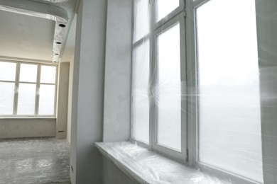 Photo of Big windows covered with plastic film in room