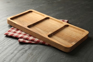 Photo of New wooden compartment tray and kitchen towel on dark grey table