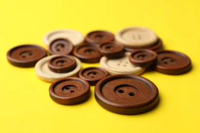 Photo of Many colorful sewing buttons on yellow background, closeup