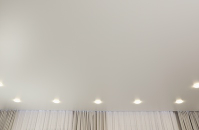 Photo of White ceiling with lamps indoors, below view