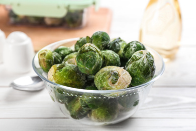 Photo of Frozen Brussels sprouts on white wooden table, closeup. Vegetable preservation