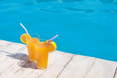 Refreshing cocktails near outdoor swimming pool on sunny day. Space for text