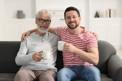 Happy son and his dad with cups at home