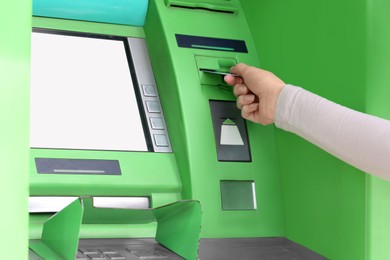 Woman inserting credit card into green cash machine, closeup