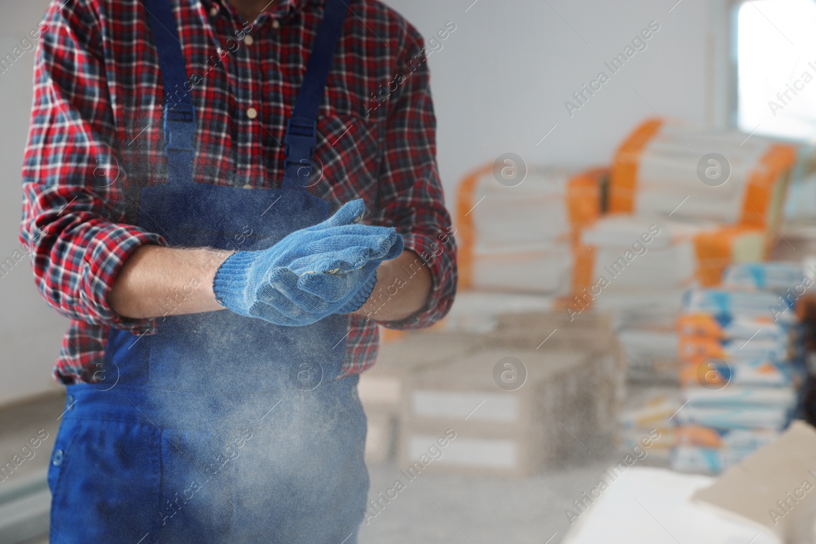 Photo of Construction worker shaking off dust from hands in room prepared for renovation, closeup