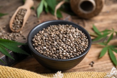 Bowl with hemp seeds on wooden table, closeup