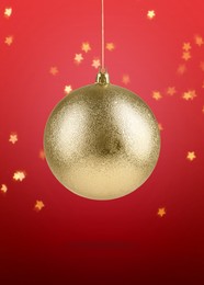 Image of Beautiful golden Christmas ball hanging on red background