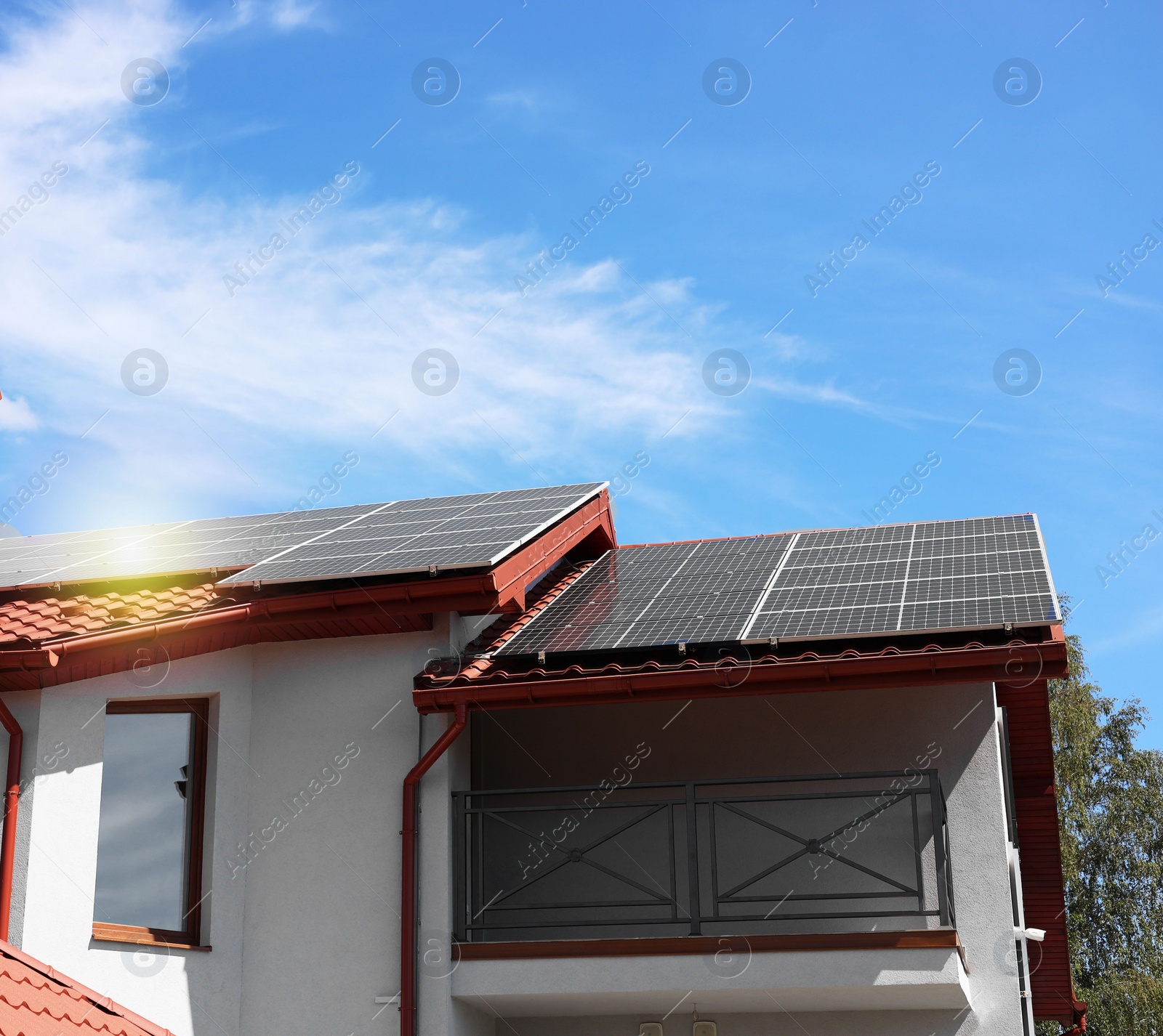 Photo of House with installed solar panels on roof under blue sky. Alternative energy source