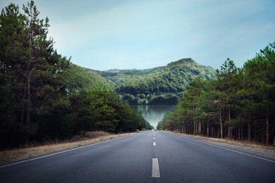 Image of Beautiful view of forest and empty asphalt road leading to mountains
