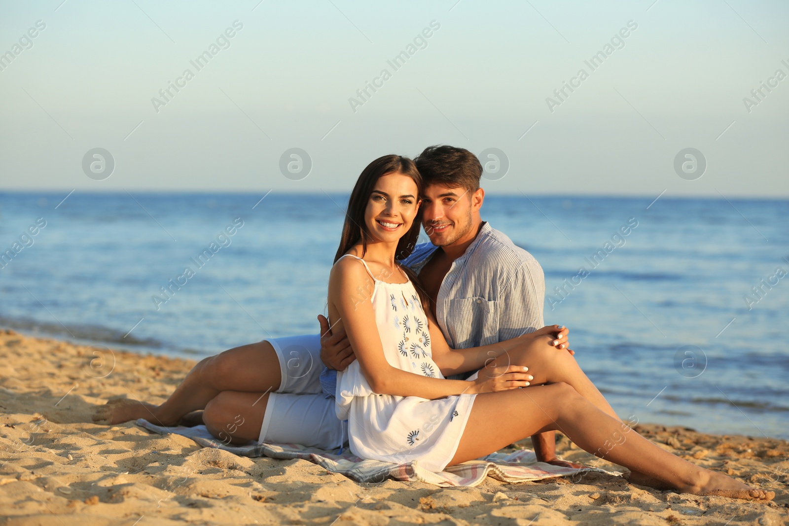 Photo of Happy young couple sitting together on beach