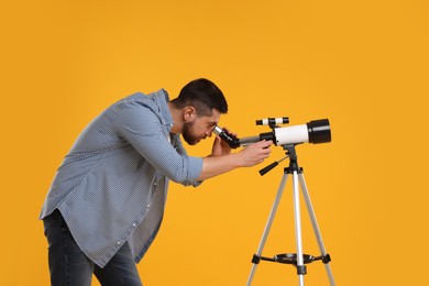 Astronomer looking at stars through telescope on orange background
