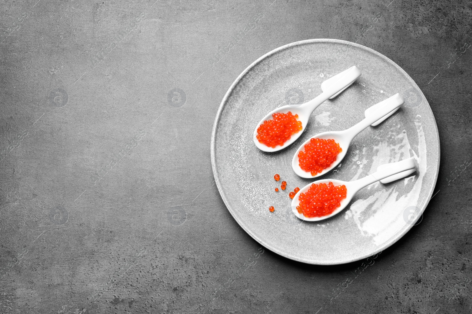 Photo of Spoons with delicious red caviar on plate