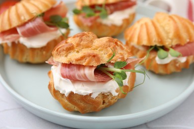 Photo of Delicious profiteroles with cream cheese and prosciutto on plate, closeup