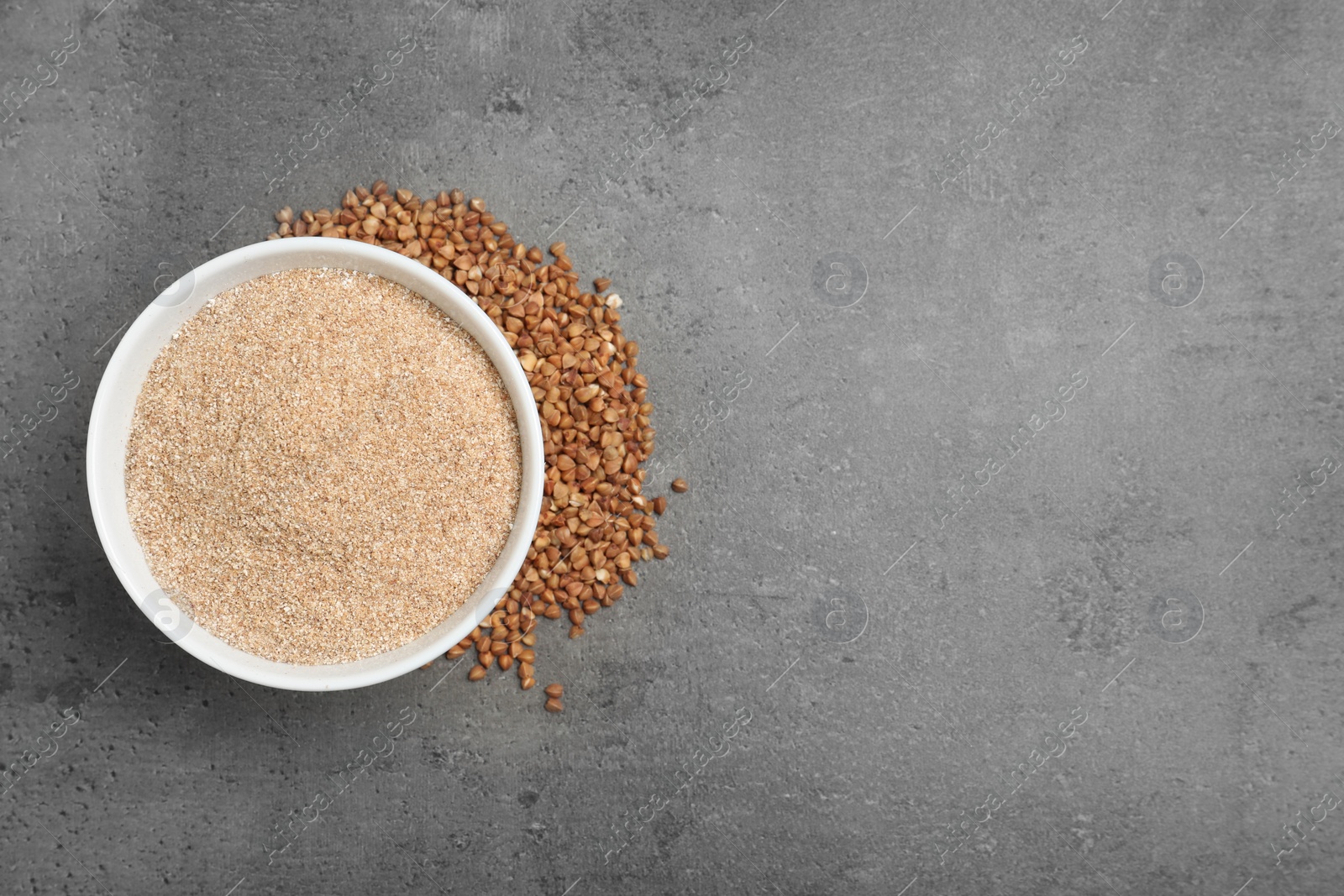 Photo of Bowl with buckwheat flour and seeds on grey background, top view. Space for text