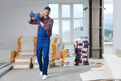 Photo of Construction worker with new building materials in room prepared for renovation