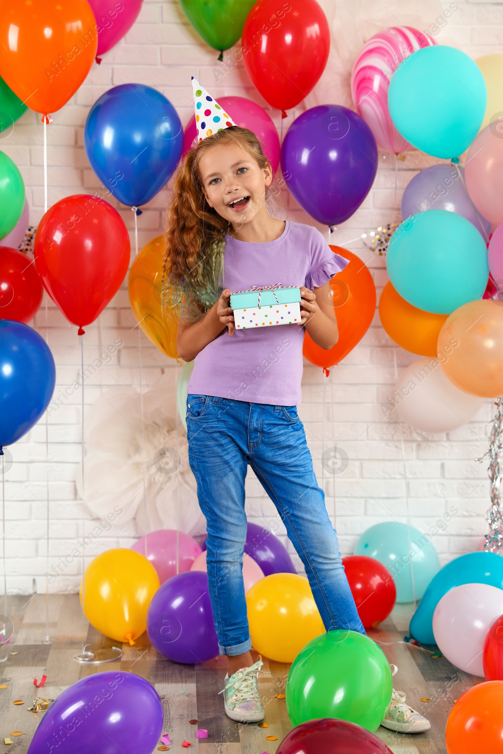 Photo of Happy girl with gift box at birthday party indoors