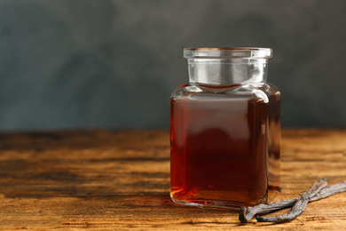 Photo of Homemade vanilla extract on wooden table, closeup. Space for text