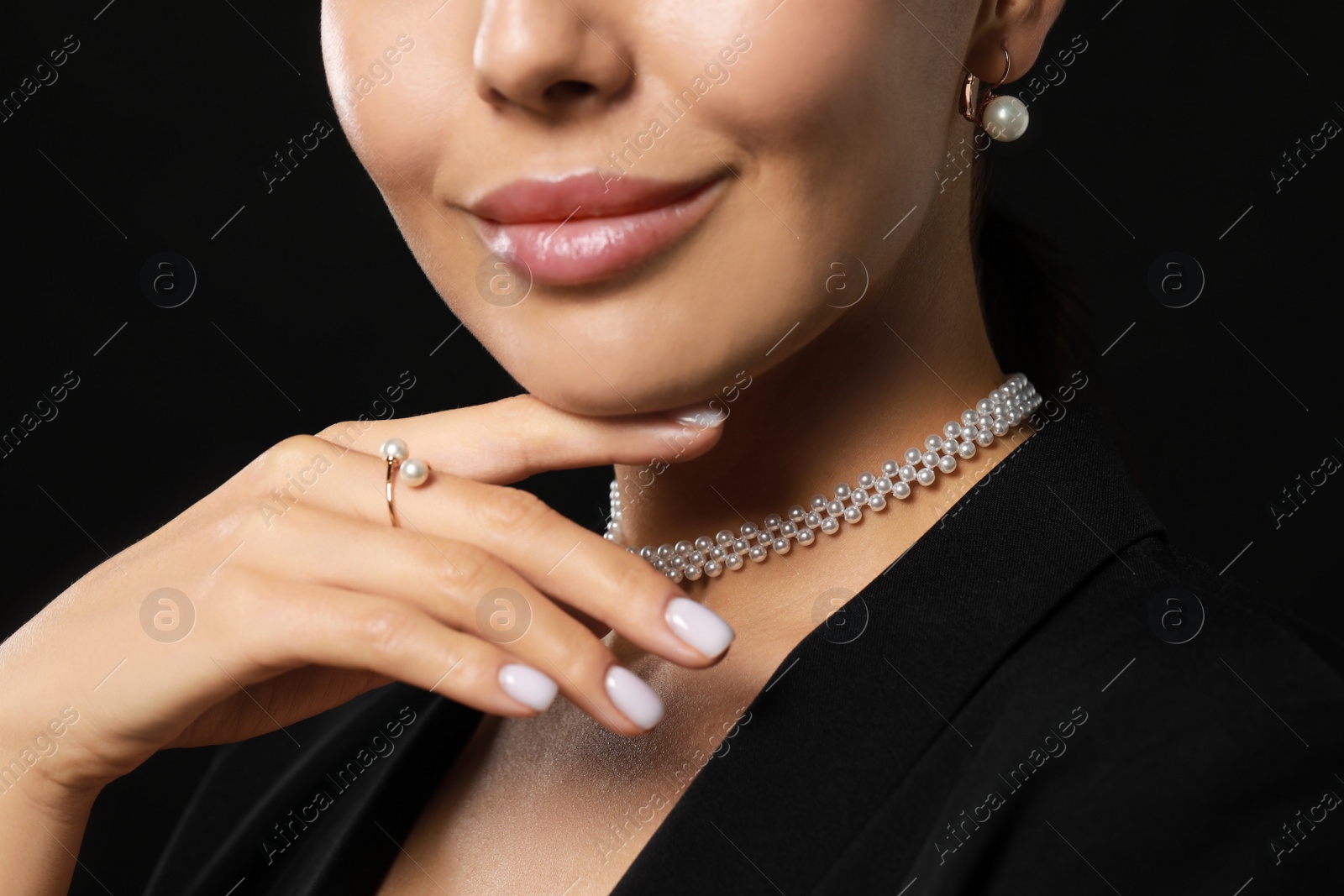 Photo of Young woman with elegant pearl jewelry on black background, closeup