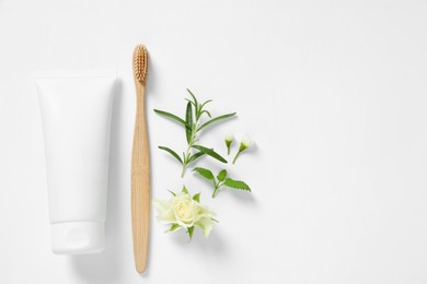 Flat lay composition with toothbrush, toothpaste, herbs and flowers on white background. Space for text