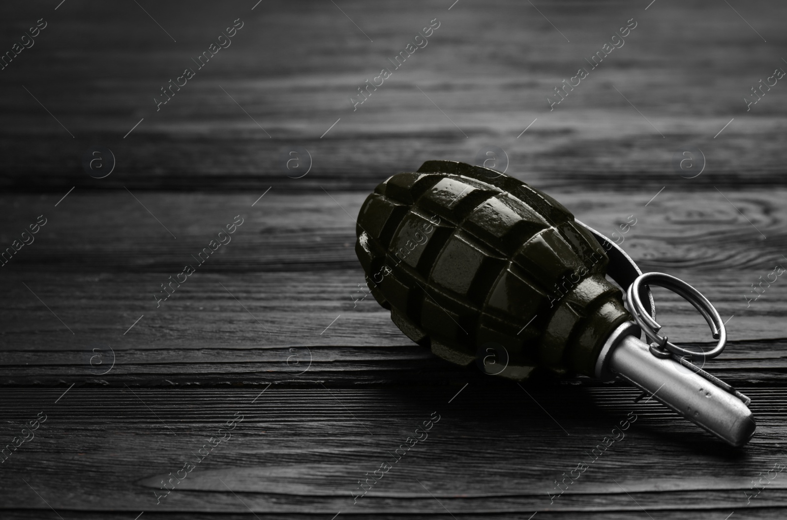 Photo of Hand grenade on black wooden table. Space for text