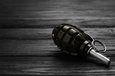 Photo of Hand grenade on black wooden table. Space for text
