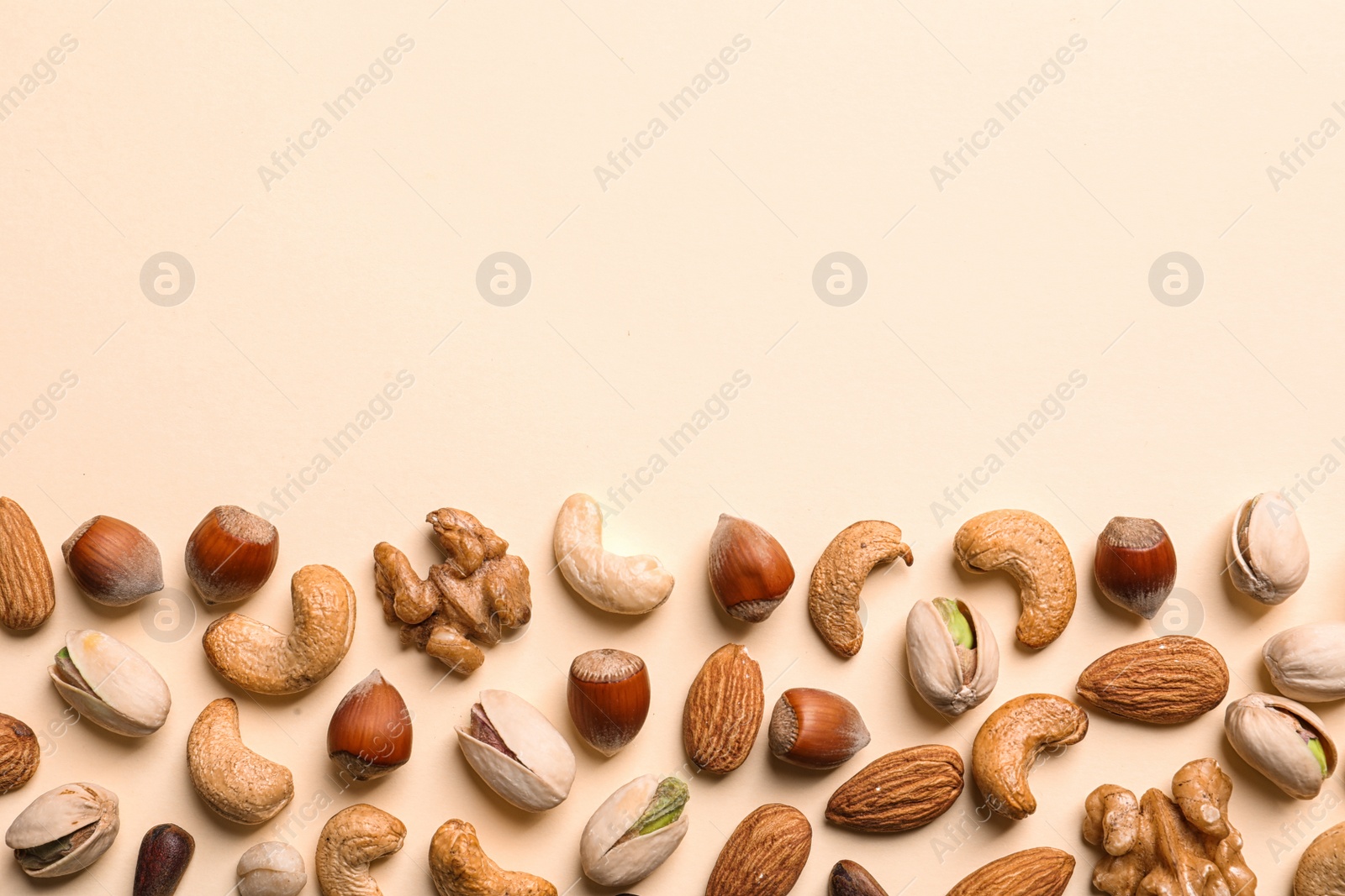 Photo of Flat lay composition with organic mixed nuts and space for text on color background