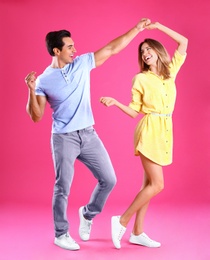 Photo of Beautiful young couple dancing on pink background