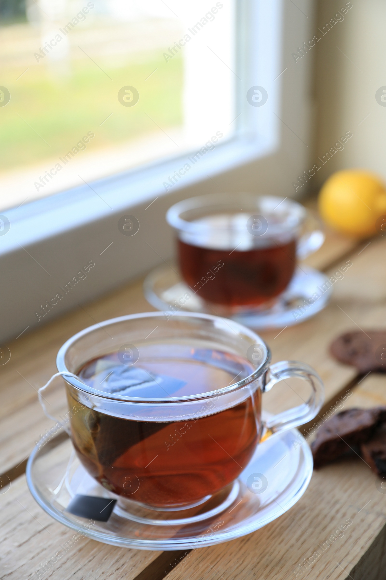 Photo of Bag of black tea in cups on wooden table indoors
