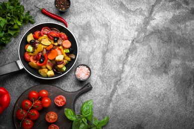 Photo of Frying pan with tasty cooked vegetables and fresh ingredients on grey table, flat lay. Space for text