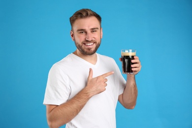 Handsome man with cold kvass on blue background. Traditional Russian summer drink