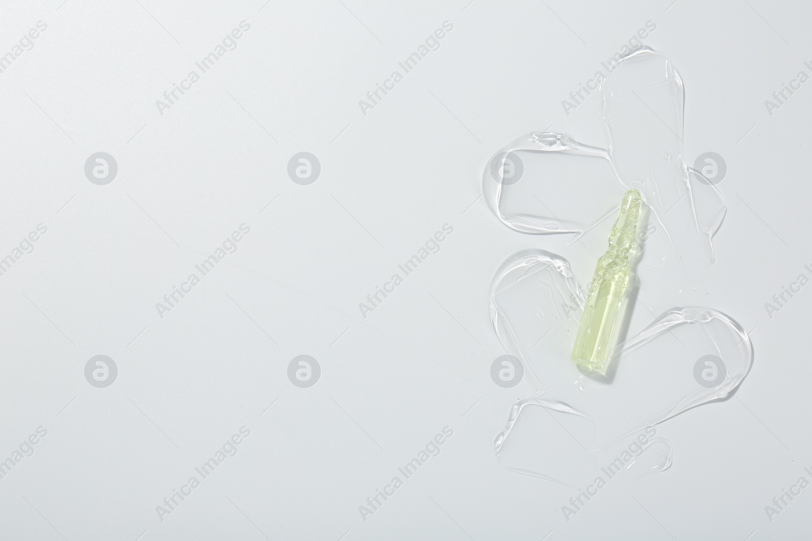 Photo of Skincare ampoule on white surface with gel, top view. Space for text