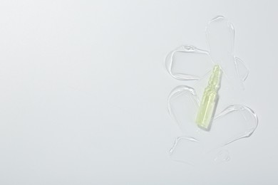 Photo of Skincare ampoule on white surface with gel, top view. Space for text