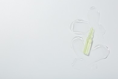 Skincare ampoule on white surface with gel, top view. Space for text