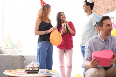 Photo of Young people having birthday party in decorated room