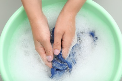 Photo of Woman washing color clothes in basin, closeup