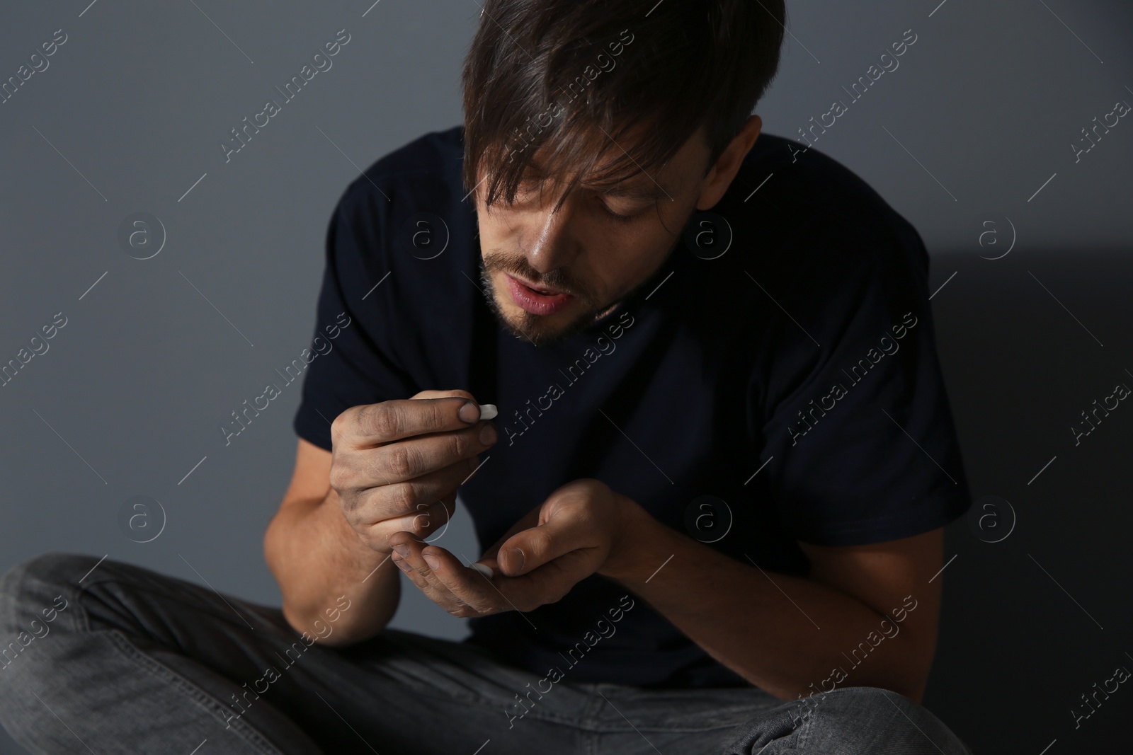 Photo of Young addicted man with drugs on grey background