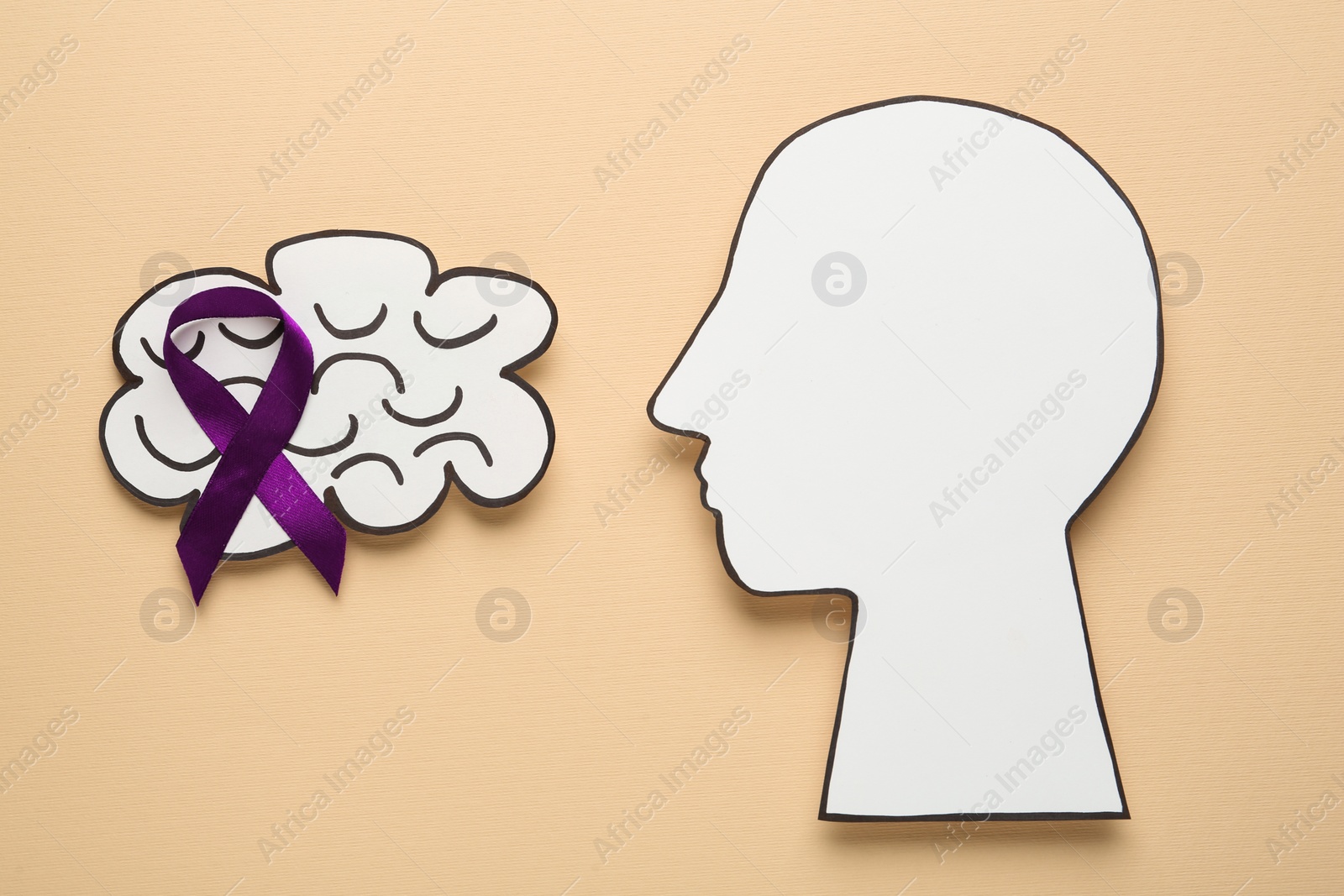 Photo of Human head and brain cutouts with purple ribbon on yellow background, flat lay. Epilepsy awareness