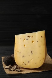 Photo of Delicious cheese and fresh truffles on black wooden table. Space for text