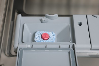 Photo of Open dishwasher door with detergent tablet, closeup