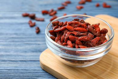 Photo of Dried goji berries on blue wooden table, closeup